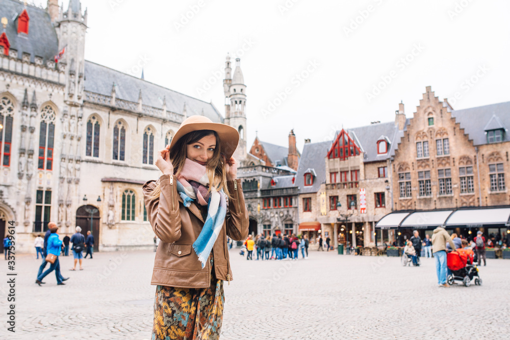 Fototapeta premium dziewczyna patrzy na zabytkowy budynek w Brugii