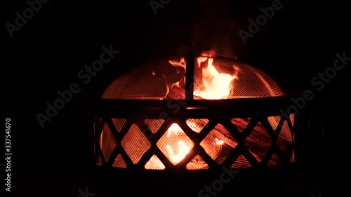 Burning wooden logs in an outdoor fireplace on a dark night.