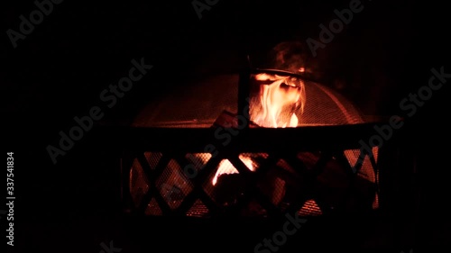Burning wooden logs in an outdoor fireplace on a dark night.