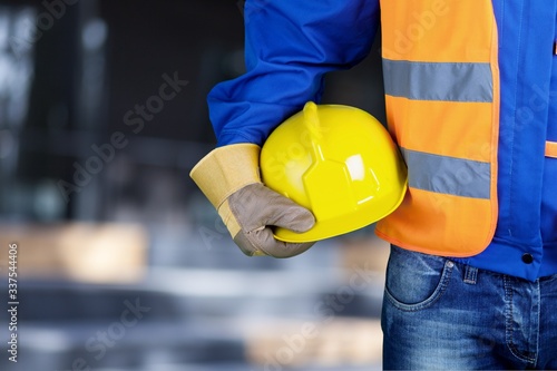 Worker man with a helmet in hands on background