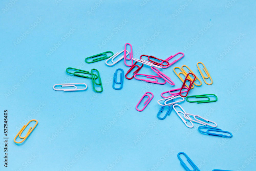 Multicolored paper clips on a blue background. Set of colorful paper clips isolated on Blue background Multicolored paper clips on a blue background. Set of colorful paper clips isolated on Blue background