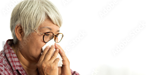 Fototapeta Naklejka Na Ścianę i Meble -  Sick senior asian woman blowing her nose with paper tissue and sneezing while having cold.health care and medicine