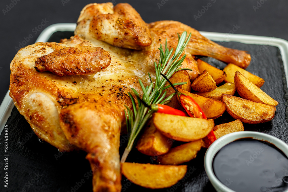 appetizing grilled chicken with homemade potatoes and sauce on a black tray appetizing grilled chicken with homemade potatoes and sauce on a black tray