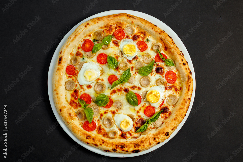 delicious Italian pizza with chicken sausages, eggs and basil on a black table delicious Italian pizza with chicken sausages, eggs and basil on a black table