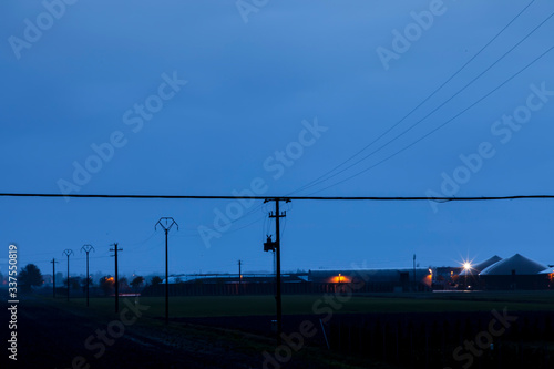 Panorama caratteristico della pianura padana. Cavi della tensione elettrica e capannoni dell 'industria agricoltura nel Polesine. Fotografia notturna.
