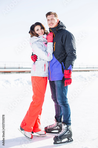 Beautiful young family couple caucasian man and sexy girl on skates huggs, stands on ice outdoors, active lifestyle vacation, romantic leisure weekend, happy winter holiday photo