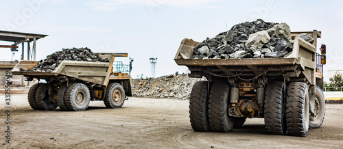 Two industrial dump trucks full loaded back view ready to unloading low angle