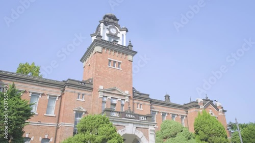 Camera tilt down from blue sky to reveal historic Daehan Hospital brick building front facade in Seoul National University Hospital complex in South Korea photo