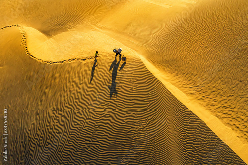 Aerial view of Woman carrying basket at sunset in Bau Trang sand dune, as sun...