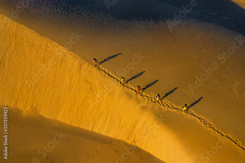 Aerial view of Woman carrying basket at sunset in Bau Trang sand dune, as sun...