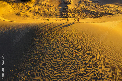 Aerial view of Woman carrying basket at sunset in Bau Trang sand dune, as sun...