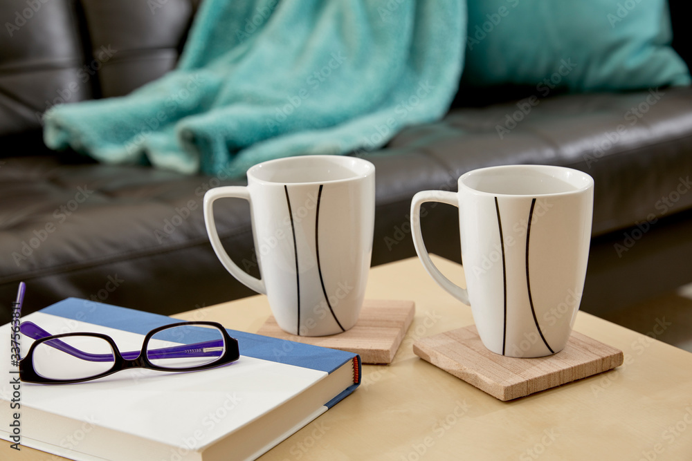Two Mugs, a book and reading glasses on a table Two Mugs, a book and reading glasses on a table