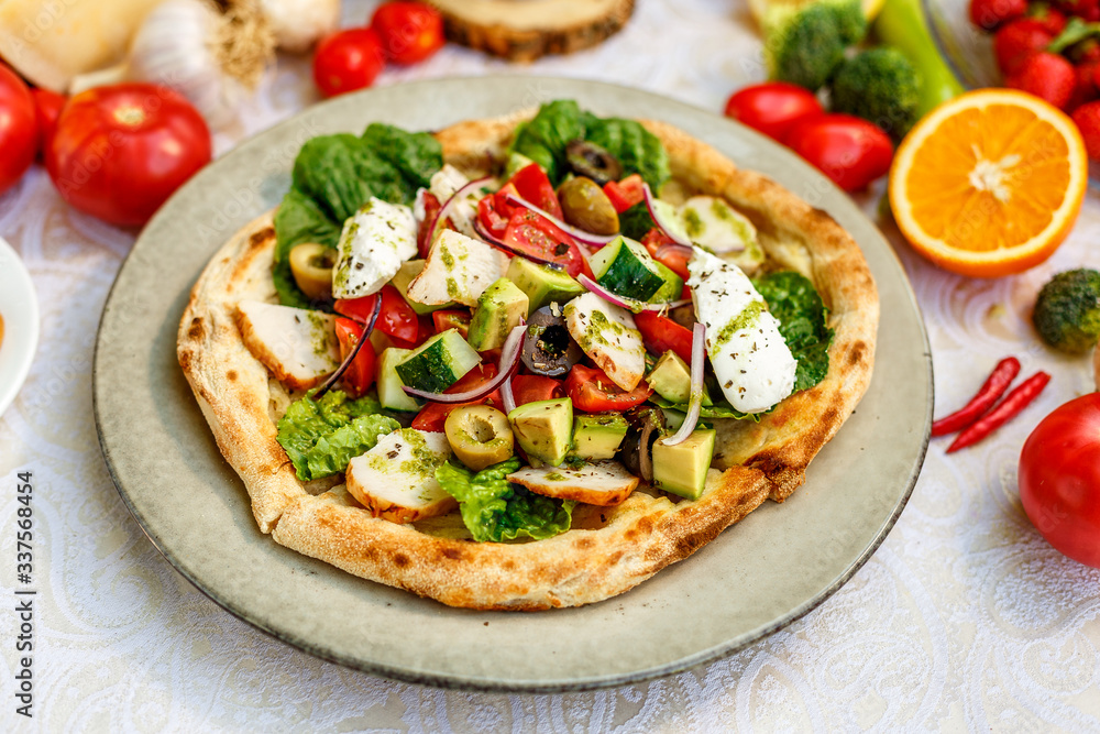 salad with chicken cheese and vegetables on a flat cake on a decorated table