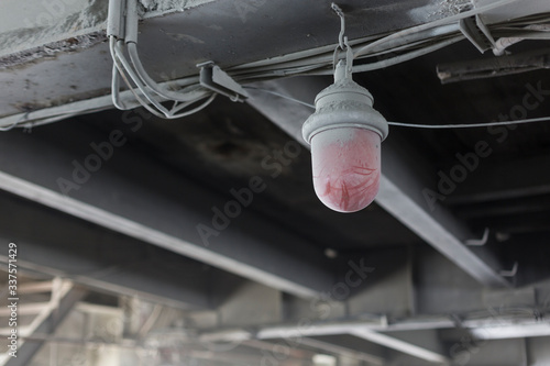 dusty red lamp under dirty iron beams in a mining workshop