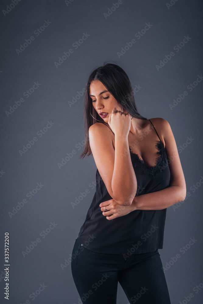 Sensual studio portrait of a sexy woman standing with one arm crossed on a gray background Sensual studio portrait of a sexy woman standing with one arm crossed on a gray background