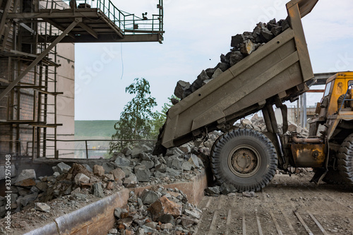 Mining industry: heavy dump truck unload granite into huge rock crusher