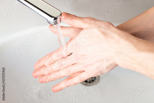 Washing hands under a stream of water in the bathroom over the sink. Close-up of men's hands. Coronavirus, Covid-19
