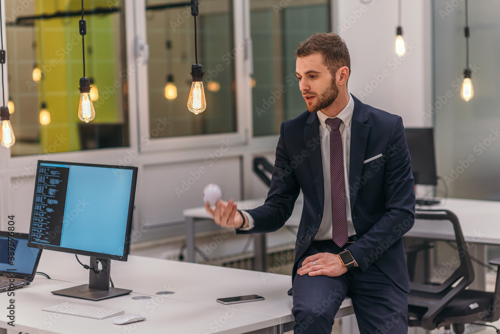 Formally dressed businessman (boss) leaning on a desk in modern an office Formally dressed businessman (boss) leaning on a desk in modern an office