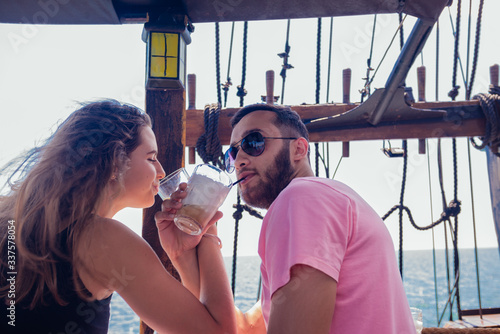 Young couple in love drinking coffee on a boat and enjoying the sea