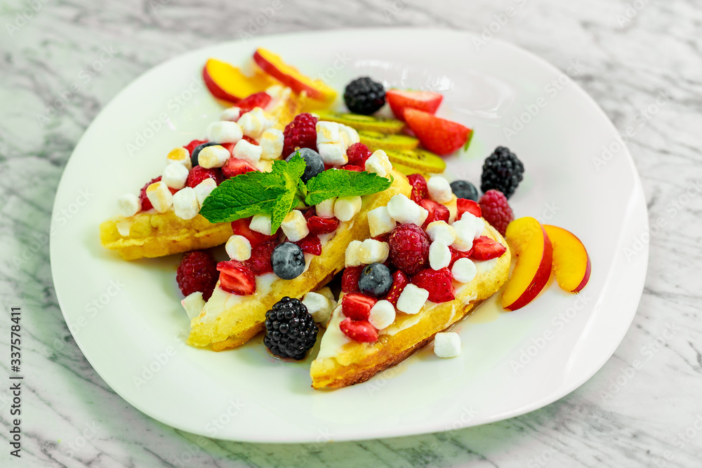 Belgian waffles with nuts, chocolate and fruit on a white plate, beautiful serving
