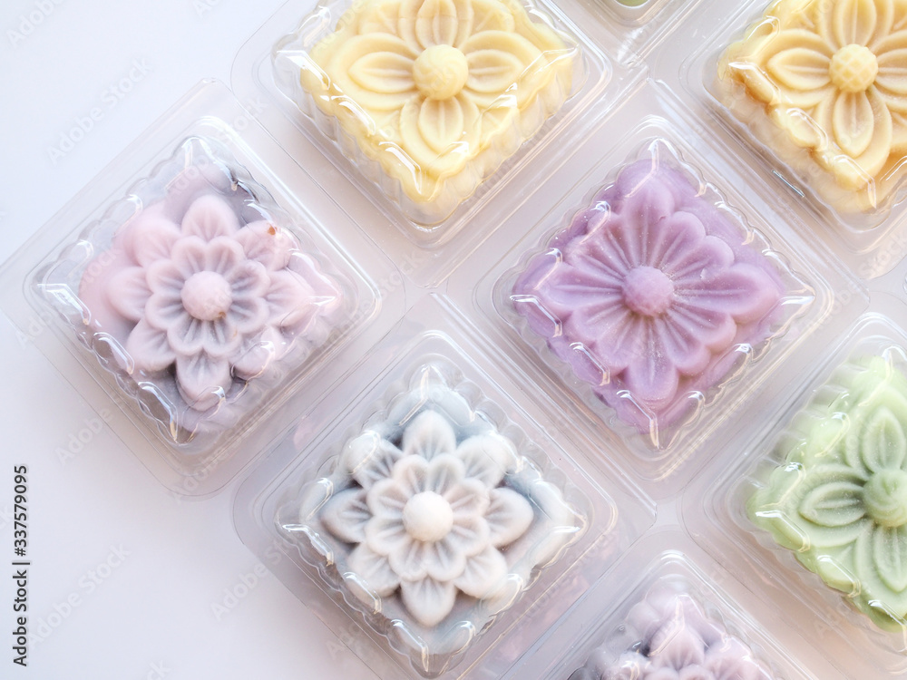 Top view of colorful snow lotus dessert, mooncake, bua hema in clear plastic box package isolated on white background.