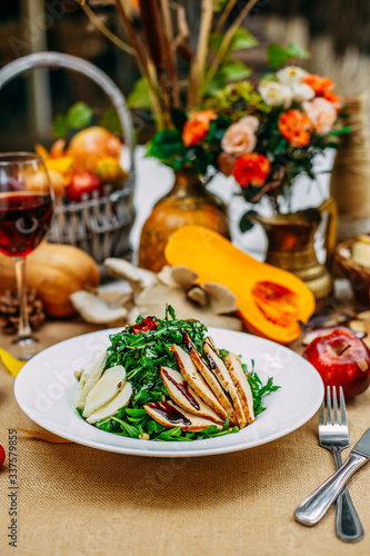 Autumn table setting with pumpkins. Thanksgiving dinner. Salad with chicken breast, cheese and arugula