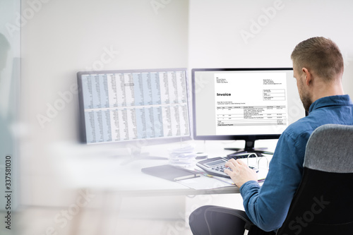 Businessman Looking At Invoice On Computer