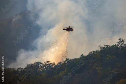 Helicopter dumping water on forest fire © toa555