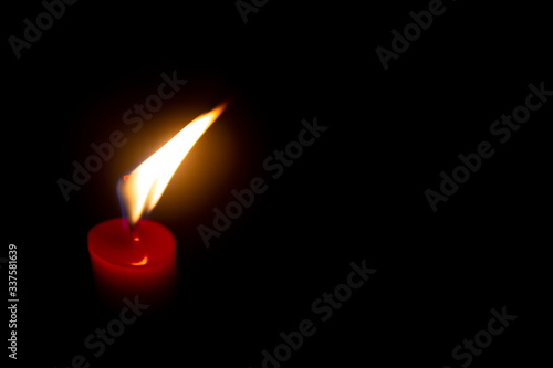 Red candle with yellow flame on black background