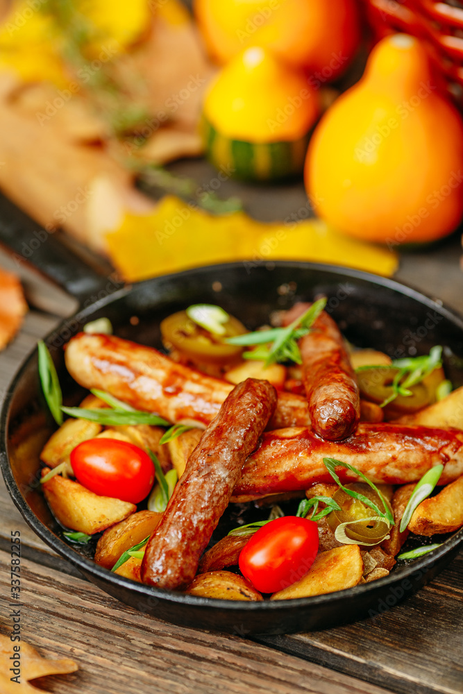 Fototapeta premium Autumn table setting with pumpkins. Thanksgiving dinner. sausages with fried potatoes in a pan