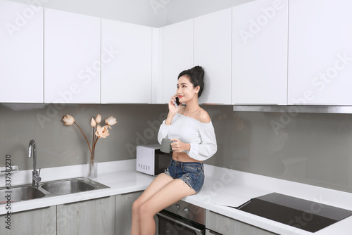Sexy girl talking by mobile phone in the kitchen