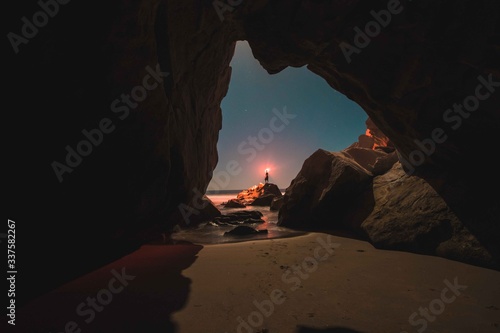 Fotografiet Man holding glowing light standing on rock at night