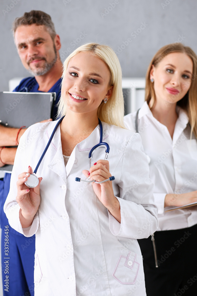 Fototapeta premium Group of medics proudly posing in row and looking in camera smiling. High level service, best treatment, 911, professional, healthy lifestyle, therapeutist consultation, physical, emergency concept