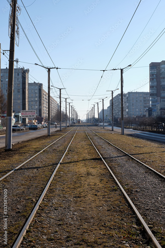 Tram tracks with poles in the city. In the distance are trams.