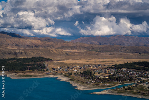 Scenic view from Mt St John Mountain Lake, with a view of the grassy hill, blue Lake Tekapo and the snow capped mountains in the background in Lake Tekapo in New Zealand South Island