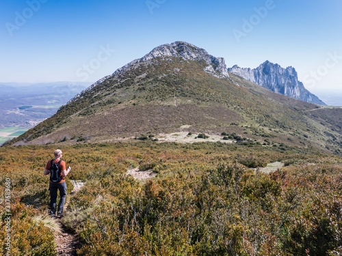 Male hiker descending a mountain and view over peak Recilla in the Cantabria mountain range between La Rioja and Alava, Basque Country, Spain photo