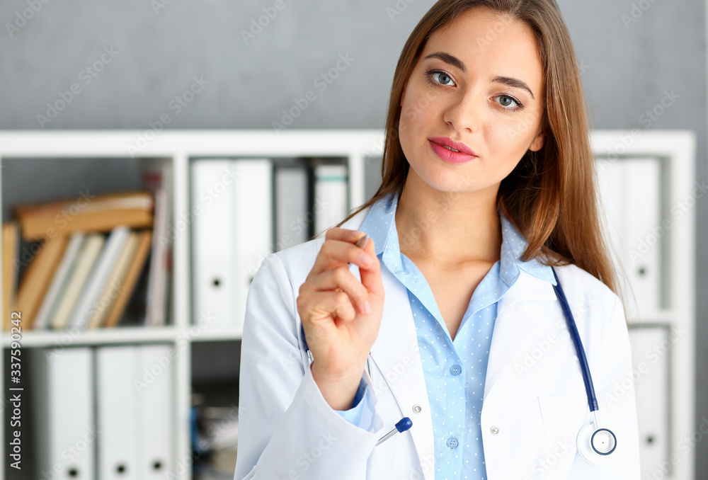Beautiful smiling female doctor hold in arm silver pen. Physical and patient disease prevention ward round exam in 911 er prescribe remedy for healthy lifestyle nurse consultant profession concept Beautiful smiling female doctor hold in arm silver pen. Physical and patient disease prevention ward round exam in 911 er prescribe remedy for healthy lifestyle nurse consultant profession concept