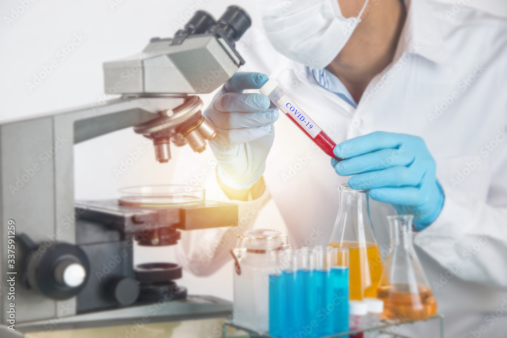 Scientist working with microscope in lab.Hold experimental Blood tube. Laboratory research concept..About experimental science such as chemical mixing or data entry to develop vaccines for everyone Scientist working with microscope in lab.Hold experimental Blood tube. Laboratory research concept..About experimental science such as chemical mixing or data entry to develop vaccines for everyone