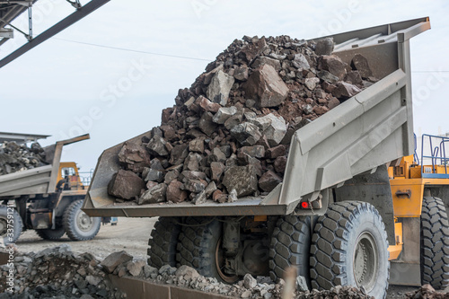 Mining industry: heavy dump trucks unload granite into huge rock crusher