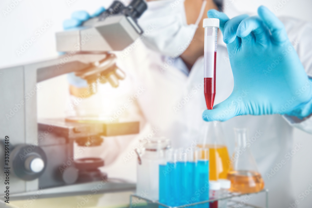 Scientist working with microscope in lab.Hold experimental Blood tube. Laboratory research concept..About experimental science such as chemical mixing or data entry to develop vaccines for everyone Scientist working with microscope in lab.Hold experimental Blood tube. Laboratory research concept..About experimental science such as chemical mixing or data entry to develop vaccines for everyone