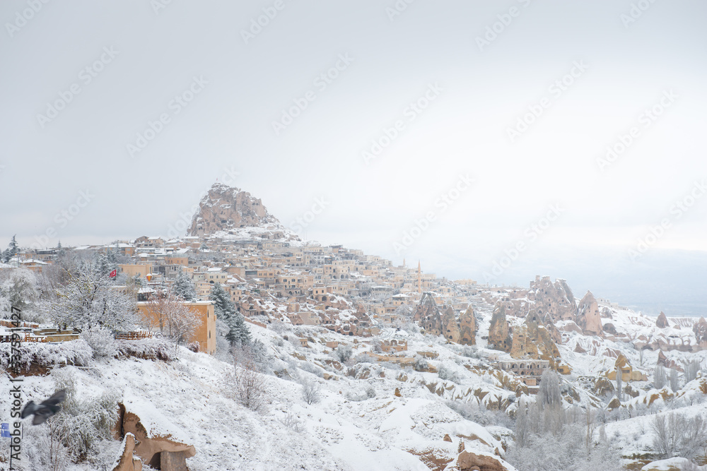 Landscape of Uchisar Castle from the Pigeon Valley with snow in the winter season at Cappadocia in Turkey