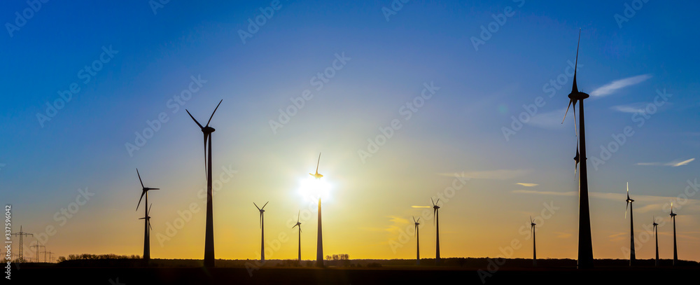 viele Windräder bei Sonnenuntergang stehen auf einem Feld und produzieren Strom
