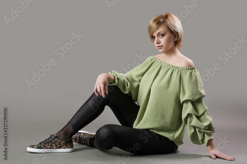 Portrait of young woman in green shirt and black leggings. Studio shot of young beautiful woman.  © triocean