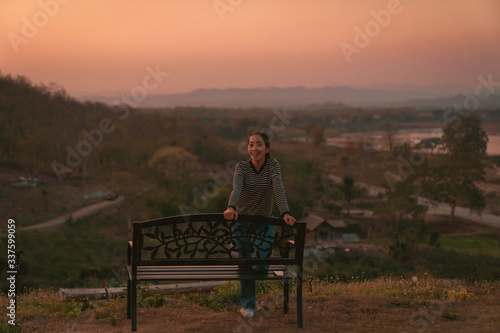 hipster girl posing smile relaxing on bench with holiday relaxing on the mountain in sunset at Northeast at Chiangkhan of Thailand photo