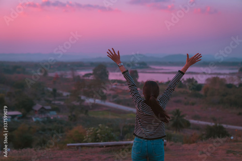 back side view hipster girl posing freedom by hand up relaxing with holiday relaxing on the mountain in sunset at Northeast at Chiangkhan of Thailand