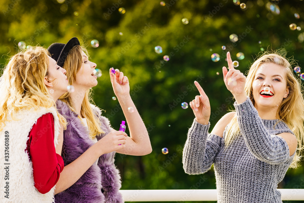 Obraz premium Women blowing soap bubbles, having fun