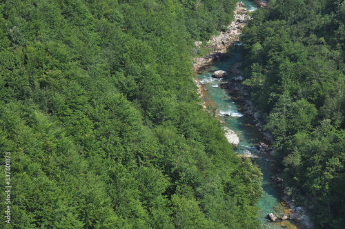 The bridge on the Tara River in Montenegro and the bridge connecting the two banks of the canyon. A stony bed of a clean river flowing through the valley along the road on a mountain slope.