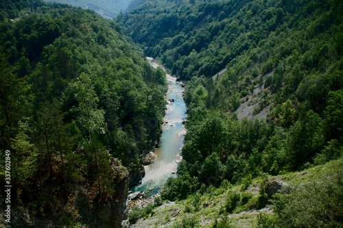The bridge on the Tara River in Montenegro and the bridge connecting the two banks of the canyon. A stony bed of a clean river flowing through the valley along the road on a mountain slope.