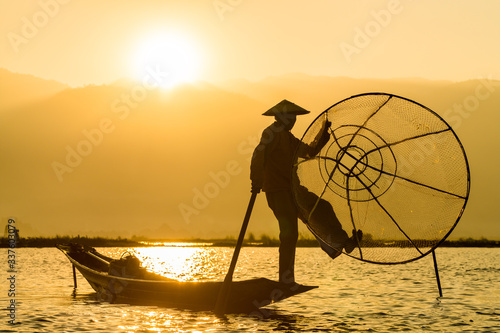 Myanmar travel attraction landmark - Traditional Burmese fishermen with fishing net at Inle lake in Myanmar famous for their distinctive one legged rowing style photo