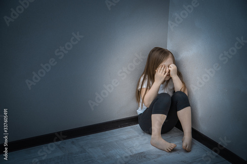 Unhappy Child Sitting In Corner Of Room